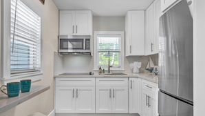 A modern kitchen with white cabinets, a stainless steel refrigerator, and a window with blinds. - Bungalow #4 - 2 Bed/1 Bath & Pool in Islamorada (Islamorada)