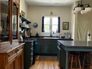 Una cocina con armarios de madera, estufa, fregadero y taburetes de bar.