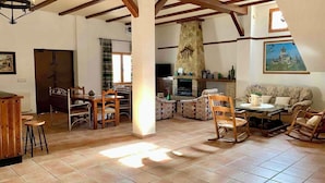A spacious living area with a fireplace, wooden furniture, and a stone wall. - Rural house El Arado (Baena)