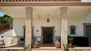 A covered outdoor area with a tiled floor, two brick pillars, a door, and potted plants. - Rural house El Arado (Baena)