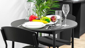 Een eettafel gedekt met borden, bestek en een fruitschaal.