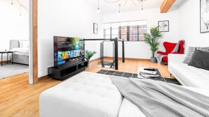 Een moderne woonkamer met een flatscreen televisie, een bank, een rode stoel en een trap.