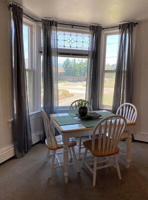 Enjoy meals in this cozy dining area with a table for four, surrounded by comfortable chairs and a beautiful bay window.