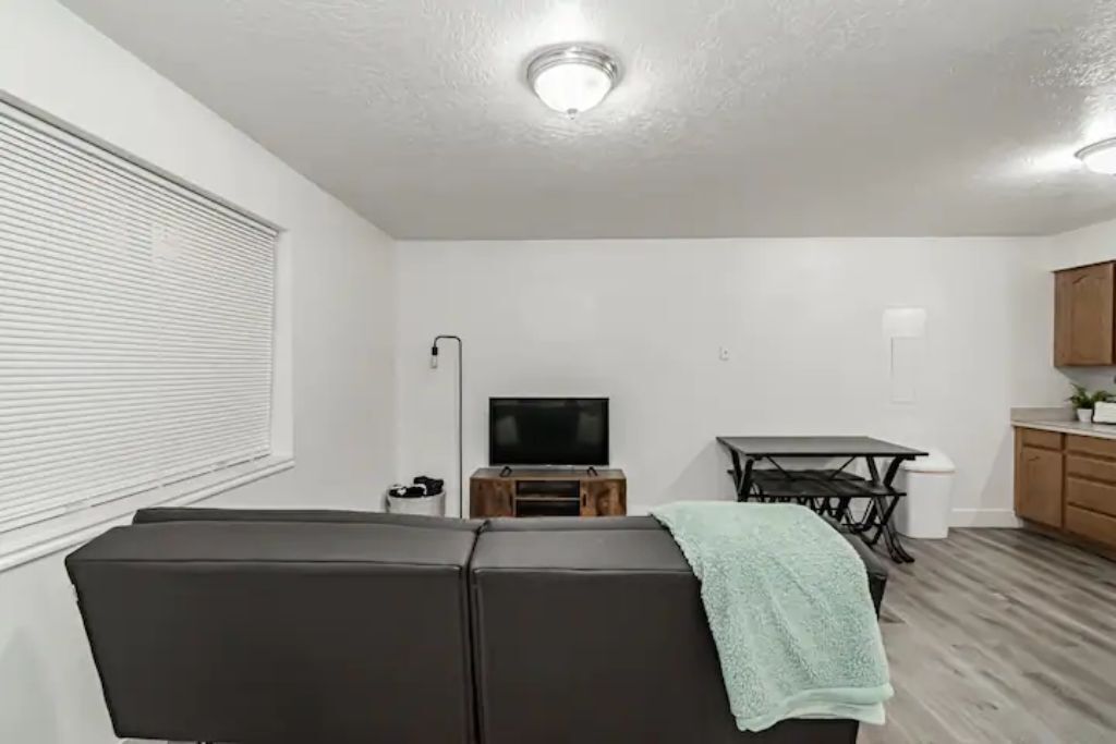 Un salon moderne avec un canapé d’angle, un téléviseur à écran plat et une table à manger.