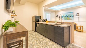 Una cocina moderna con una isla central, electrodomésticos integrados y un tragaluz.