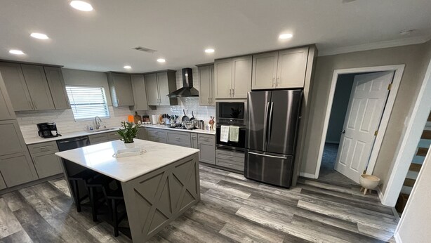 A modern kitchen with a large island, stainless steel appliances, and a herringbone wood floor. - Large Remodeled Central Located Minutes to the Beach & Downtown Free Big Parking (Pensacola)