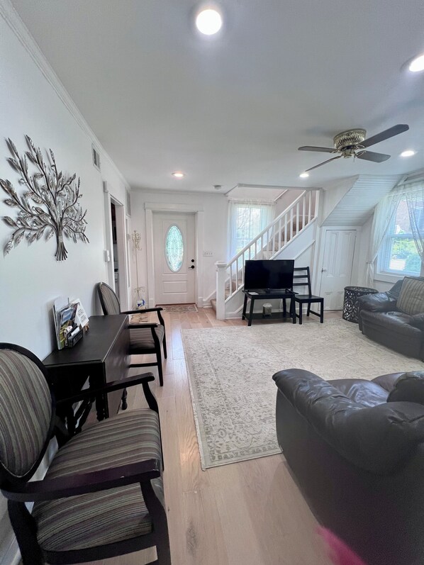 A living room with a dining area, a staircase, and a television.