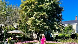 A woman standing in a well-manicured garden with hedges and flower beds. - 1-Min Walk to The Inn • Private Suite, Tub & Full Kitchen. (Washington)