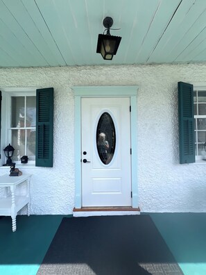 A white door with a decorative glass panel, a black lantern above it, and a white textured wall.