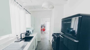 A modern kitchen with a black Galanz refrigerator, white cabinets, and a grey countertop. - Pink, Architect-Appointed House! 3 min from JTNP. (TWENTYNINE PALMS)