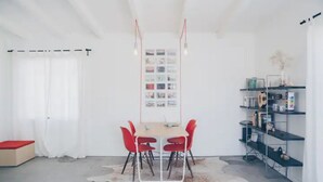 A modern room with a dining table, red chairs, a white cowhide rug, and a wall-mounted shelf with various items. - Pink, Architect-Appointed House! 3 min from JTNP. (TWENTYNINE PALMS)
