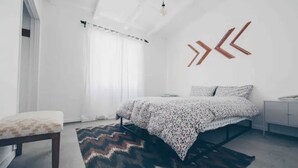 A modern bedroom with a bed, a bench, and a geometric wall decoration. - Pink, Architect-Appointed House! 3 min from JTNP. (TWENTYNINE PALMS)