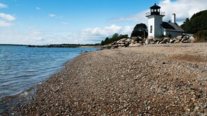 A lighthouse on a pebbly beach with clear skies. - Iconic Bristol Ferry Lighthouse (Bristol)