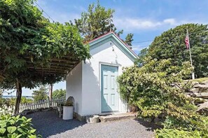 A charming guest house surrounded by lush greenery, featuring a light blue door and a red roof.