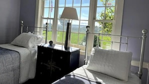 A bedroom with two beds, a nightstand, and a window with a view of the outdoors. - Iconic Bristol Ferry Lighthouse (Bristol)