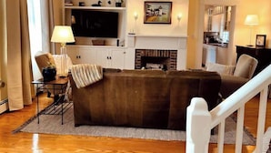 A living room with a large flat-screen TV, a fireplace, and a cozy seating area. - Iconic Bristol Ferry Lighthouse (Bristol)