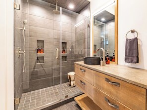 A modern bathroom with a glass-enclosed shower, a wooden vanity with a sink, and a mirror above the vanity. - Downtown Penthouse✨ City Views + Pet-Friendly + Inc. Biltmore Pass (Asheville)