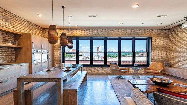 A modern kitchen with a large window, a dining area with a bench, and a seating area with a sofa and armchairs.