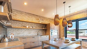 A modern kitchen with a brick backsplash, wooden cabinets, and a large island.