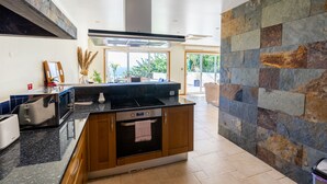 Una cucina moderna con piani di lavoro in granito, forno integrato e zoccolo a parete in pietra.