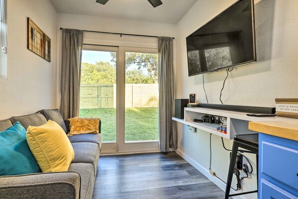 A living room with a sofa, a television mounted on the wall, and a sliding glass door leading to a backyard. - Canyon Lake Retreat w/ Pool ~ 2 Mi to Lake (Canyon Lake)