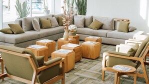 A modern living room with a large sofa, wooden side tables, and a patterned rug.