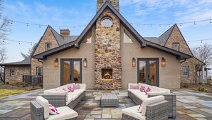 A stone house with a central fireplace, outdoor seating, and string lights.