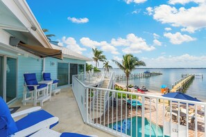 A balcony with a pool, lounge chairs, and a view of the water.