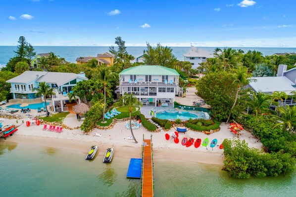 Une propriété située en bord de mer, comprenant une grande maison, une piscine et une jetée qui s’avance dans l’eau.