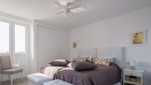 Een moderne slaapkamer met een bed, een stoel, een nachtkastje en een plafondventilator.