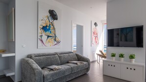 Een moderne woonkamer met een grijze bank, een witte console en kunstwerken aan de muren.