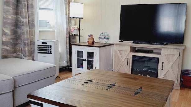 Een woonkamer met een houten salontafel, een bank, een televisie, een open haard en een klok.