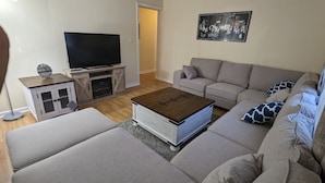 Een woonkamer met een bank, een salontafel, een televisie en een kast.