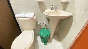 A bathroom with a toilet, sink, and green trash bin. - Ayenda Republicano Colonial No 2 (Santa Marta)