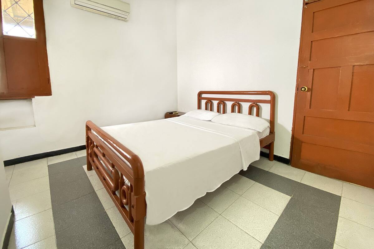 A single-bed room with a wooden headboard, a nightstand, and a door.