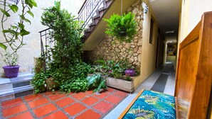 A courtyard with a tiled floor, potted plants, a staircase, and a wooden door. - Ayenda Republicano Colonial No 2 (Santa Marta)
