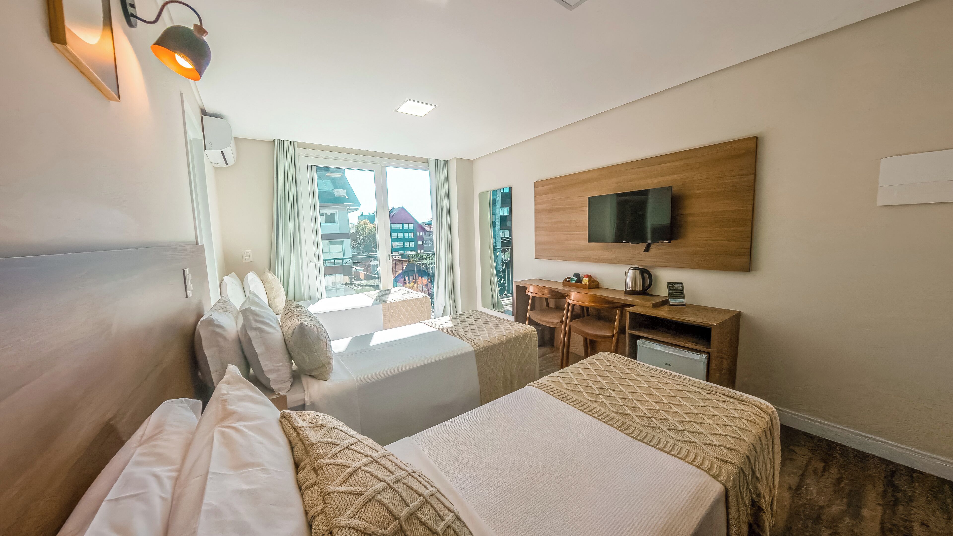 Une chambre d’hôtel avec deux lits, un bureau, une télévision et une fenêtre donnant sur un paysage agréable.