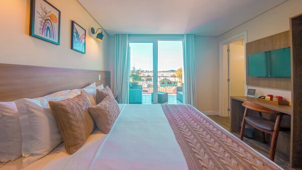 A hotel room with a bed, a desk, a TV, and a balcony with a view.