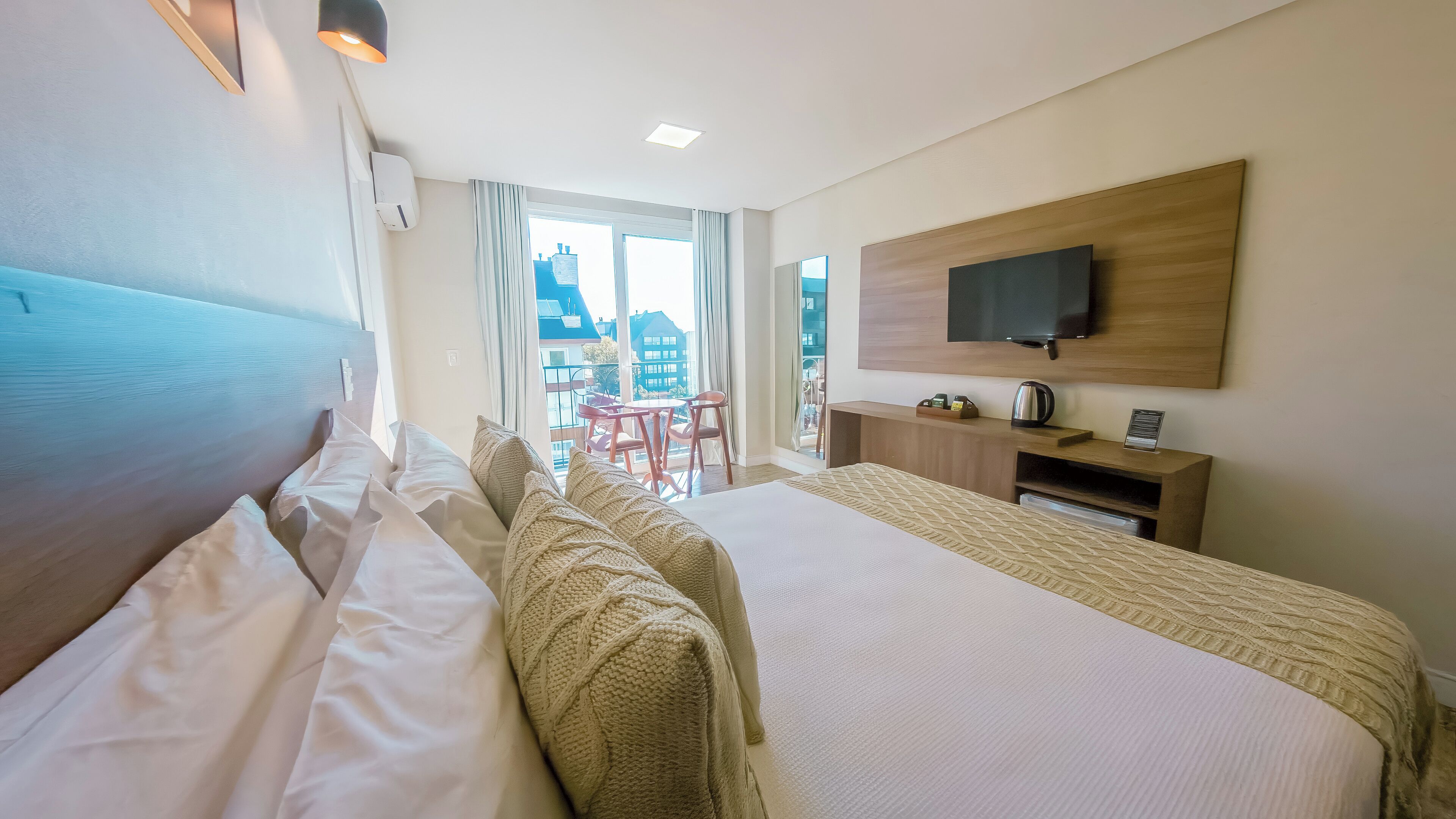 Habitación de hotel con dos camas, televisión, escritorio y vistas a edificios.