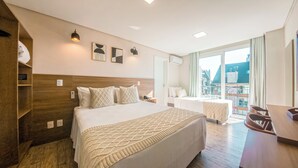 Una habitación de hotel con cama, mesitas de noche, escritorio y balcón con vistas.