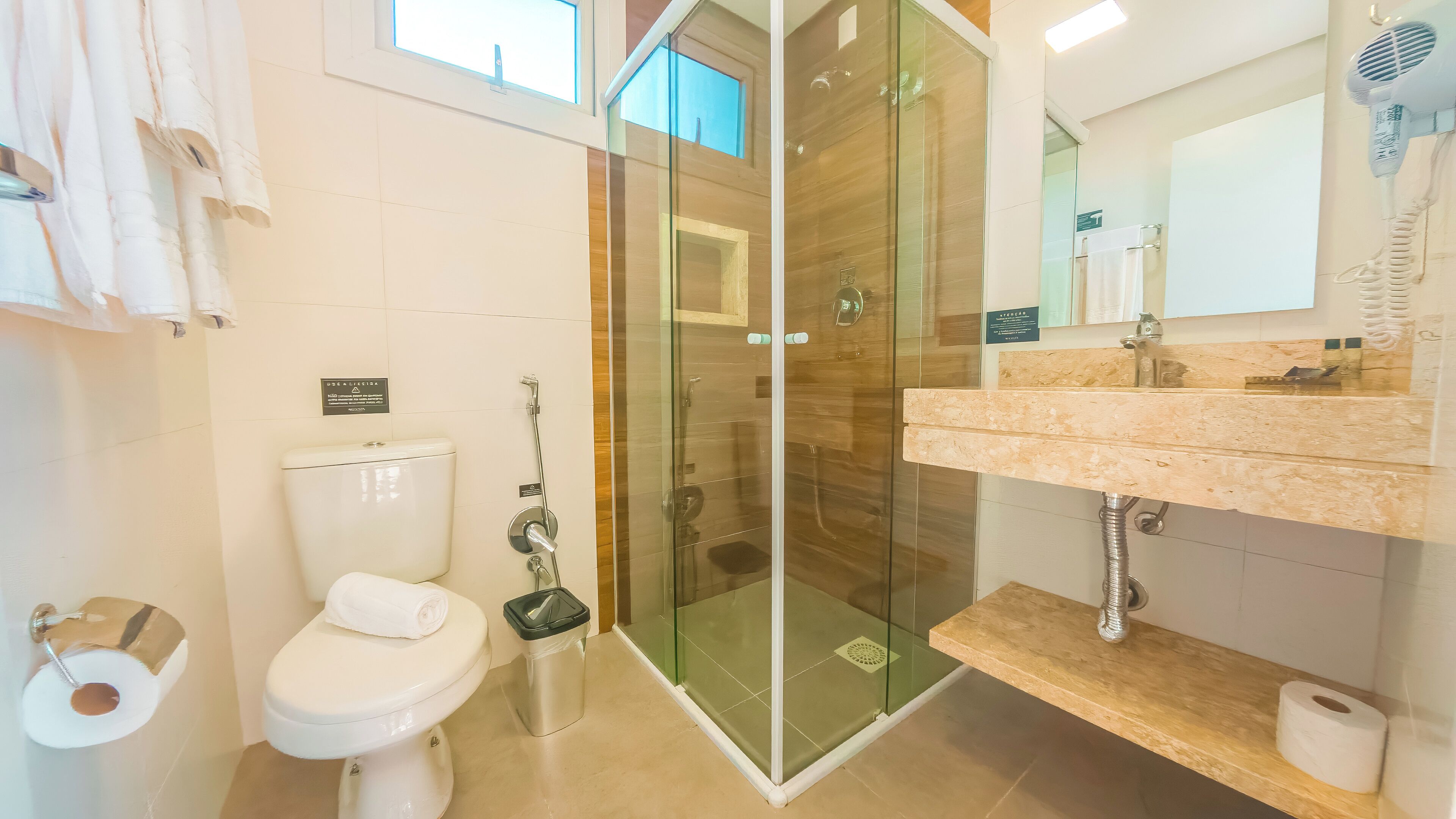 A modern bathroom with a glass-enclosed shower, a toilet, and a sink with a marble countertop.