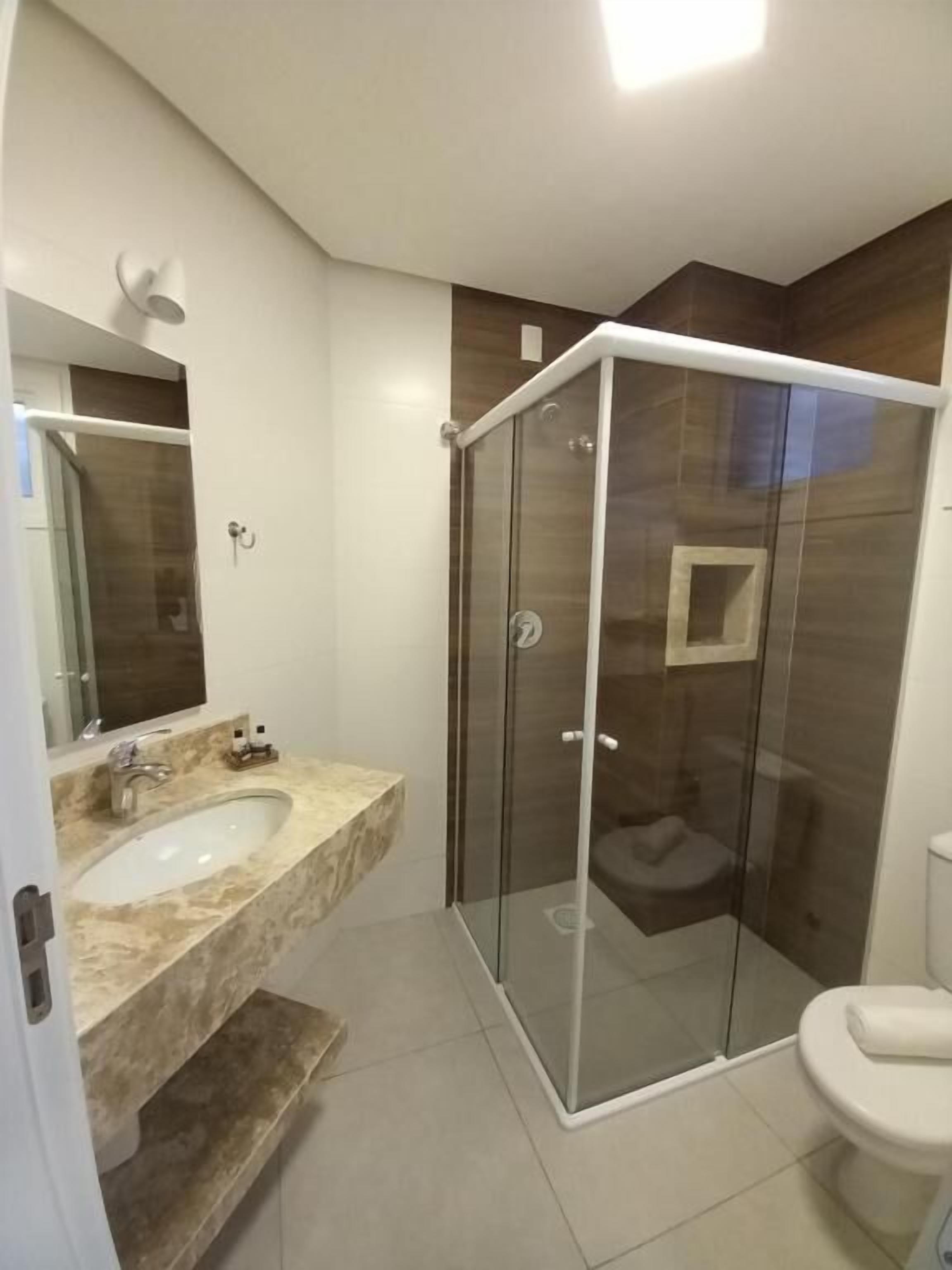 Un bany modern amb dutxa d'estuc de vidre, un lavabo de marbre i un vàter.