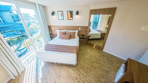 Habitación de hotel con una cama grande, piso de madera, balcón con vistas y una obra de arte en la pared.