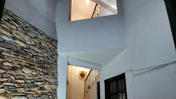 Una escalera con peldaños decorados que conduce a una plataforma, una pared de piedra y un banco.