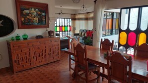Un comedor con una mesa y sillas de madera, un armario de madera y un cuadro en la pared.