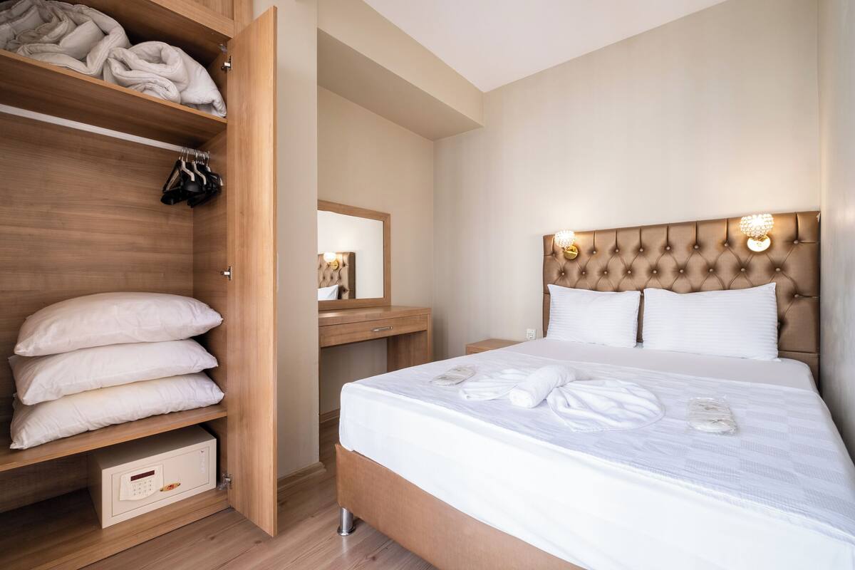 A neatly organized bedroom with a bed, a wardrobe, and a bedside table.