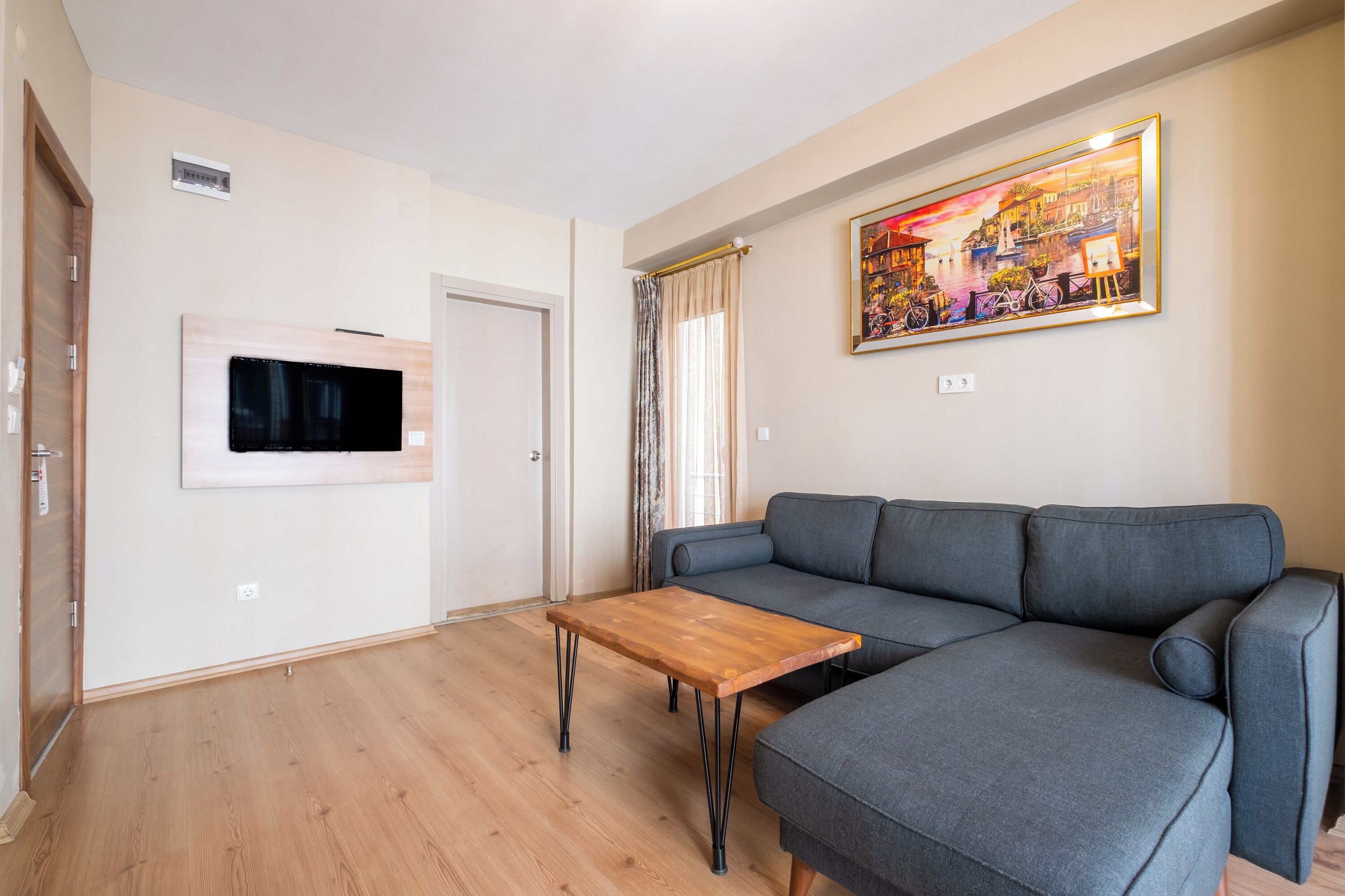 A modern living room with a grey sofa, a wooden coffee table, and a mounted TV.