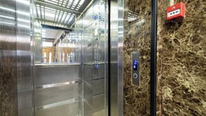 Interior de un ascensor con paredes metálicas y suelo de mármol.