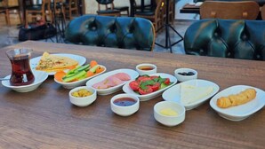 Una mesa de comedor con diversos platos y bebidas, rodeada de sillas y una pared con un mural.