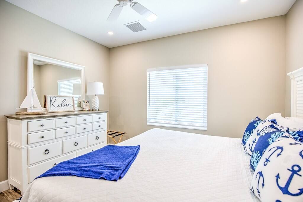 Un dormitorio con cama, cómoda, espejo y ventana con persianas.